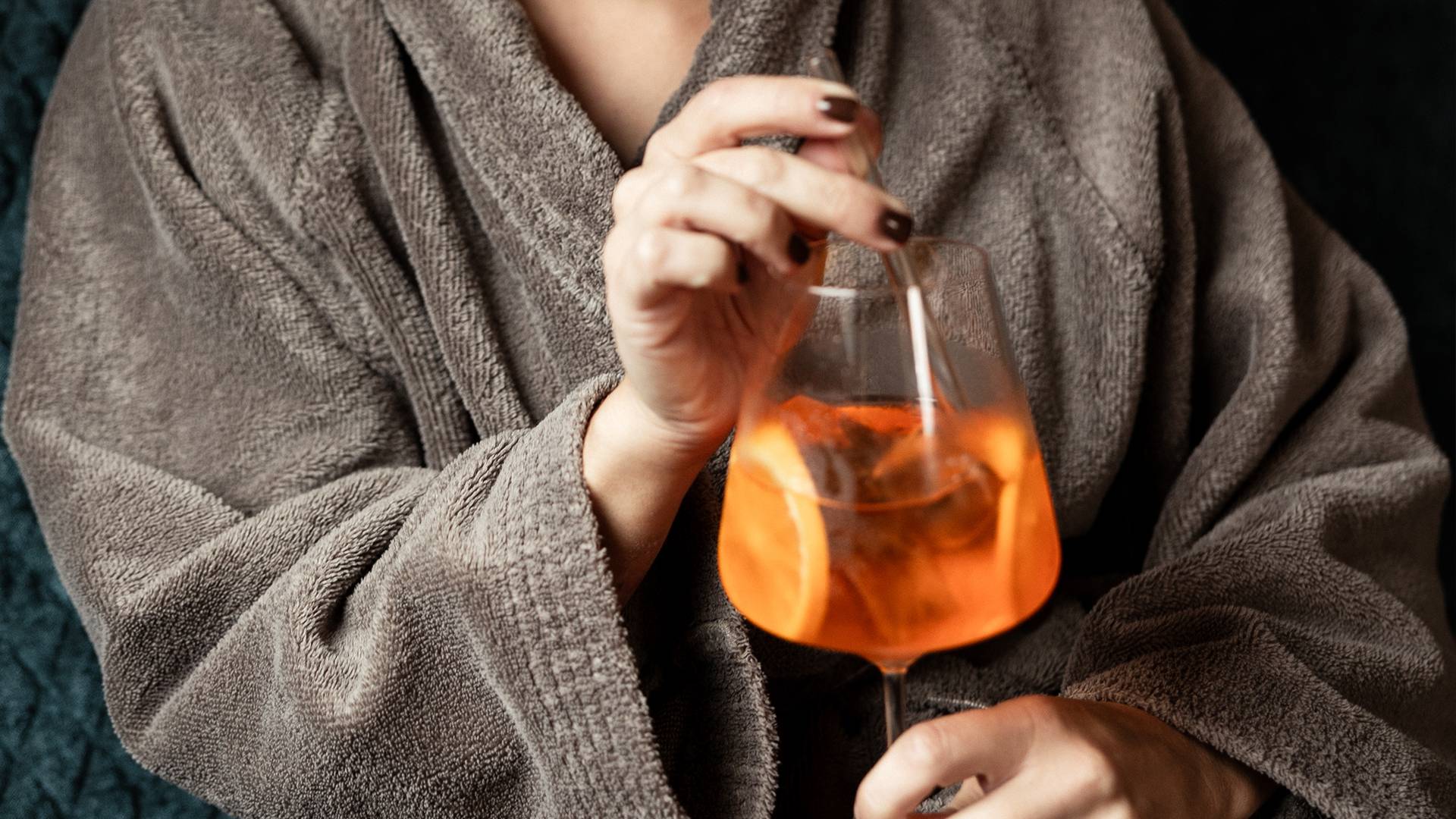 Dame im Bademantel mit einem Aperol Spritz in der Hand